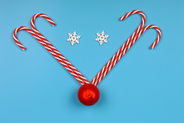 Creative christmas background. Striped candies on a blue background. Minimalistic scandy style. Empty space for text, top view, flat lay