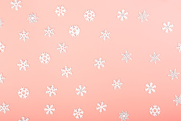 Gently pink winter background with white snowflakes. Creative christmas layout. Minimalistic Scandinavian style. Empty space for text, top view, flat lay