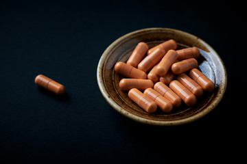 HMB (β-Hydroxy β-methylbutyric acid) capsules. Bodybuilding food supplements on black paper background.