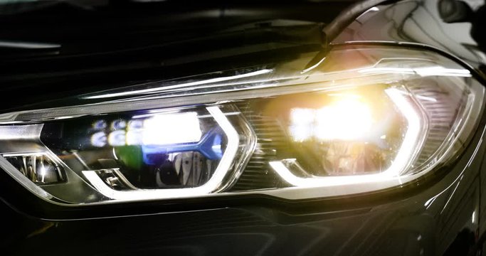 In the automobile salon (garage, center) the headlights of the car are very close, turning on (turning off) checking the front light (dimensions). Concept of: Headlight Testing, New, Diagnostics, Car.