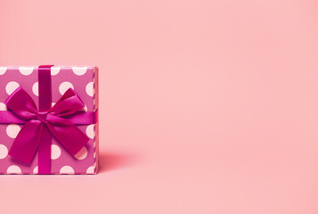 Present boxe with dots  wrapped with bright ribbon on colorful background. Festive and holiday theme. Christmas or birthday gift.