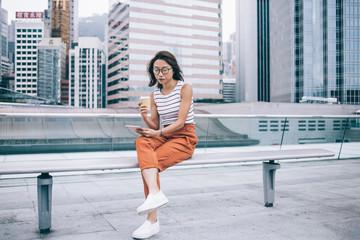 Thoughtful Asian young woman using tablet on urban bench