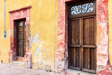 Fachada colonial amarilla de casa de pueblo con vieja puerta y ventana de madera