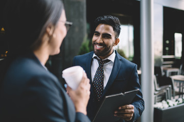 Successful male and female business experts recalls to pleasant moment together during break from work, smiling man in formal elegant wear talking with colleague while spending time outdoors