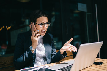 Furious angry woman dressed in formal wear reading news on content website about problems in own company and calling to employee for shouting and fire during international smartphone conversation