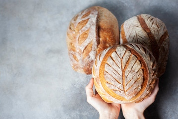 Sourdough bread. Freshly baked organic wheat bread. Child holding fresh round bread. - obrazy, fototapety, plakaty