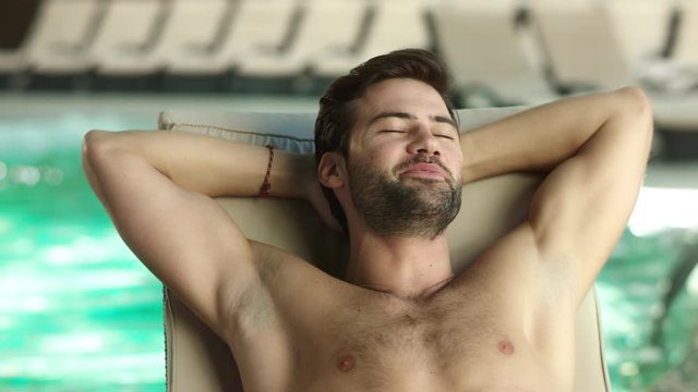 Closeup man relaxing by pool at luxury spa. Man sleeping poolside on lounger