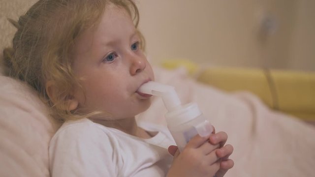 pretty upset girl breathes with inhaler to cure cough resting in comfortable bed on blurred background extreme close view