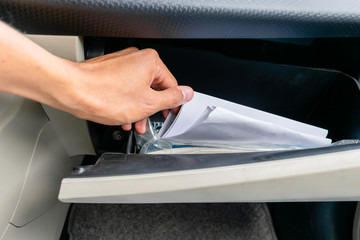 hand stirring papers in a glove box (dashboard) 