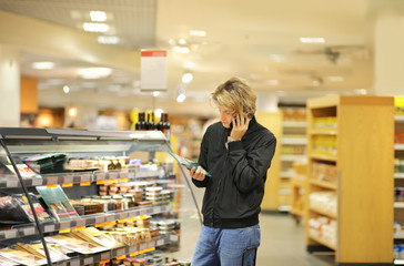 Young man shopping in supermarket, reading product information	