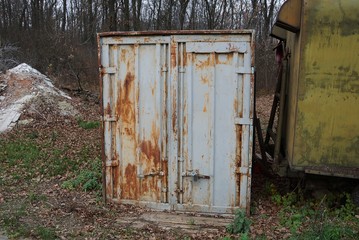 old gray iron container in rust with a closed door stands on the street