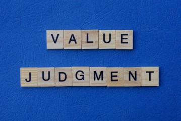 phrase value judgment made from  wooden letters lies on a blue background