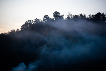Smoke on background with mountains covered with trees