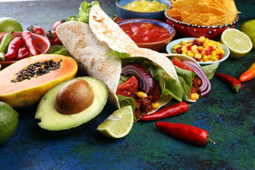 Mexican food, including tacos, guacamole, nachos and pepper on rustic table