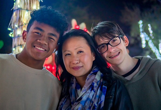 Asian mother, African American mixed son, and caucasian step son with Christmas lights.
