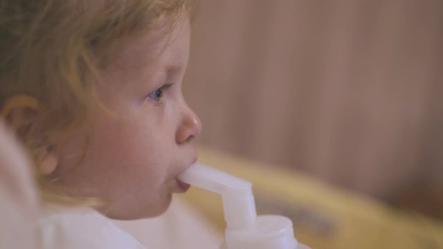 pretty little girl uses modern inhaler to cure bronchitis lying on soft bed on blurred background extreme close side view