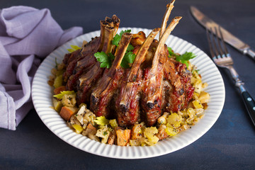 Crown roast of pork stuffed with apples and bread crumbs and celery sticks on white plate