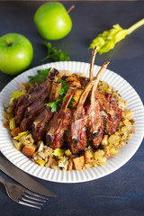 Crown roast of pork stuffed with apples and bread crumbs and celery sticks on white plate