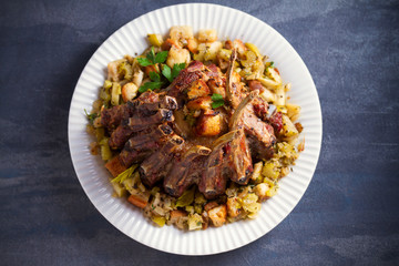 Crown roast of pork stuffed with apples and bread crumbs and celery sticks on white plate