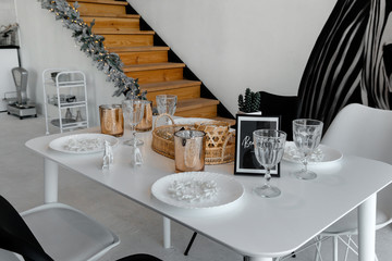 A table set with golden and glass decor for Christmas New year, stairs and lights on a background in a kitchen
