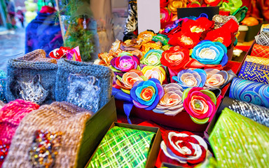 Fototapeta na wymiar Creative and bright handmade clothes for sale at stalls during Riga Christmas market in Latvia. Europe on winter. Street Xmas and holiday fair. Advent Decoration and Stalls with Crafts Items of Bazaar