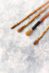 Fototapeta premium Set of brushes Fude for Sumi-e painting. Bright wooden background. Top view. Copy space. 