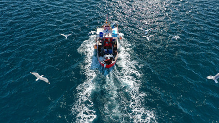 Aerial drone photo of traditional wooden fishing boat cruising in deep blue sea near port of Syros...