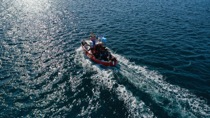 Aerial drone photo of traditional wooden fishing boat cruising in deep blue sea near port of Syros or Siros island, Cyclades, Greece