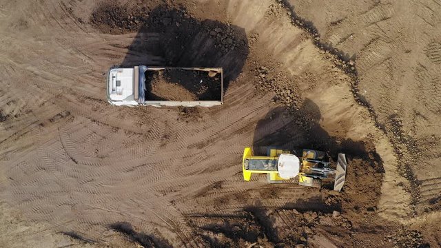 Vast Excavation site with an on going operation of Excavators loading soil onto Trucks, Aerial view.