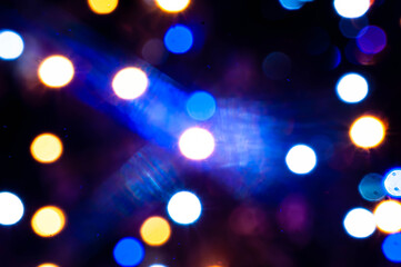 blurred defocused colorful christmas lights with sparkle and reflections on dark background with bokeh effect for wallpaper and design