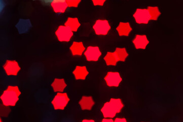 unfocused red christmas lights with stars shape on dark blurred background with copy space for wallpaper and design