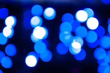 luminous and defocused blue lights on dark blurred background with bokeh effect for wallpaper and design