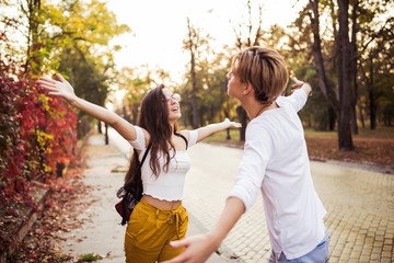 Fototapeta premium Young man meeting his girlfriend with opened arms, outdoor
