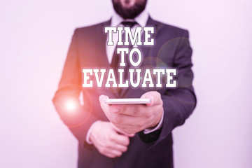 Text sign showing Time To Evaluate. Business photo showcasing moment rate used before products or service Give feedback Male human wear formal work suit hold smart hi tech smartphone use one hand