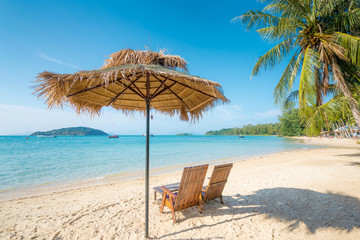 Beach Chairs and Umbrella on summer island with clear water sea and wave with speed boat in background in Phuket, Thailand. Summer, Travel, Vacation and Holiday concept.