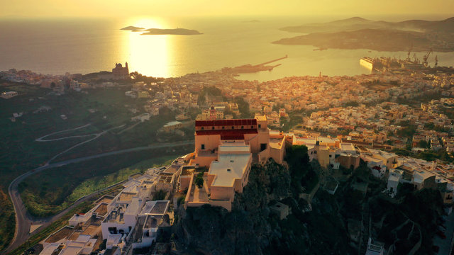 Aerial drone photo of iconic uphill Catholic settlement of ano Syra featuring church of Saint George at sunset with beautiful colours, Syros or Siros island, Cyclades, Greece