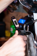 soft focus of barista hands holding silver jug with hot water and measure temperature with thermometer in cafe