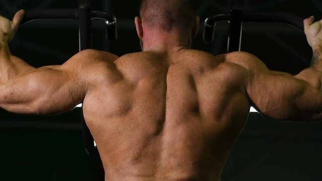 Muscular bodybuilder fitness men doing pull-ups exercises in gym naked torso. Handsome strong athletic men pumping up back muscles workout fitness and bodybuilding concept background.