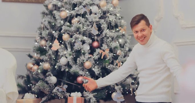 Happy dad with little son lay out gifts under the New Year tree. Boxes with presents. New Years Eve.