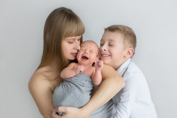 the mother holds the newborn in her arms, next to the eldest son. the first photo session of a newborn. Bros
