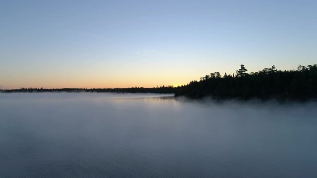 4K aerial descending flight over a fog covered lake on a misty fall morning in Northwest Ontario, Canada.