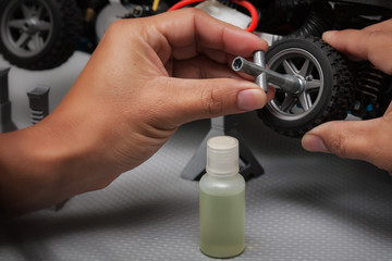 Radio controlled hobbyist removing or installing a wheel on toy car to lubricate with oil and give...