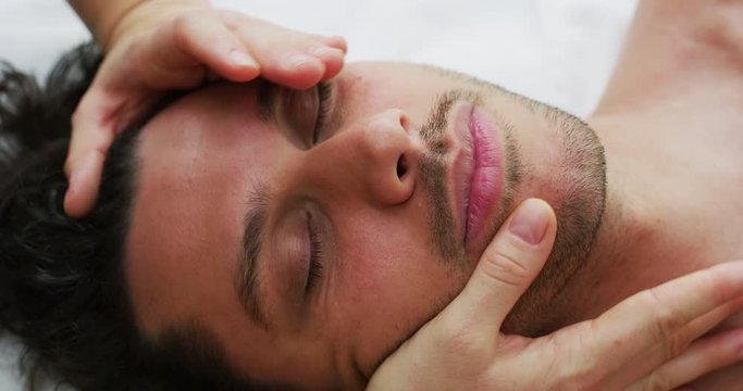 Close up of an young handsome man is receiving a facial massage and spa treatment for perfect skin in a luxury wellness center.