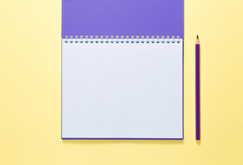 open notebook with pencil on yellow background