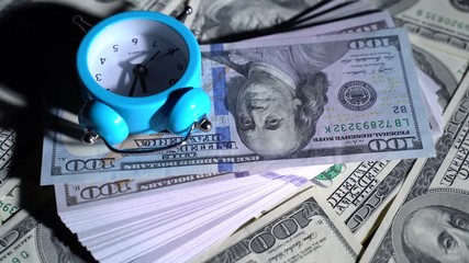 100 dollar bills and an alarm clock spinning on a table - Powered by Adobe