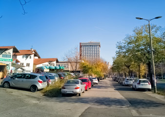 Ustanicka, Vozdovac, Belgrade, Serbia -  november 25th, 2019: street view, sidewalk and parking with houses and Hotel Serbia skyscraper in the distance