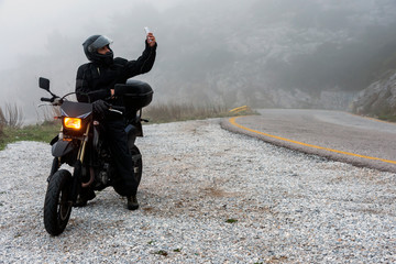 Rider is trying to find signal on his mobile on a foggy day