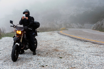 Rider is trying to find signal on his mobile on a foggy day