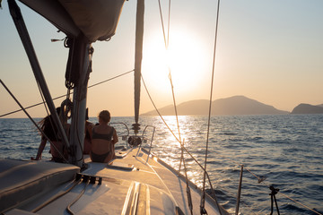 Girls sit on the deck of the yacht and enjoy the sunset