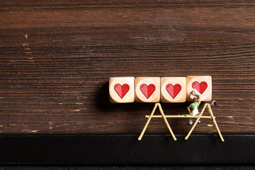 painter figure and wooden blocks with heart icons on wooden background